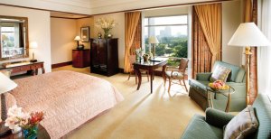 grosses modern eingerichtetes helles hotel zimmer mit viel licht und einem grossen gemütlichen bett dazu ein paar sessel und einem grossen panorama fenster für einen guten ausblick über die stadt und den park im exklusiven mandarin oriental kuala lumpur i